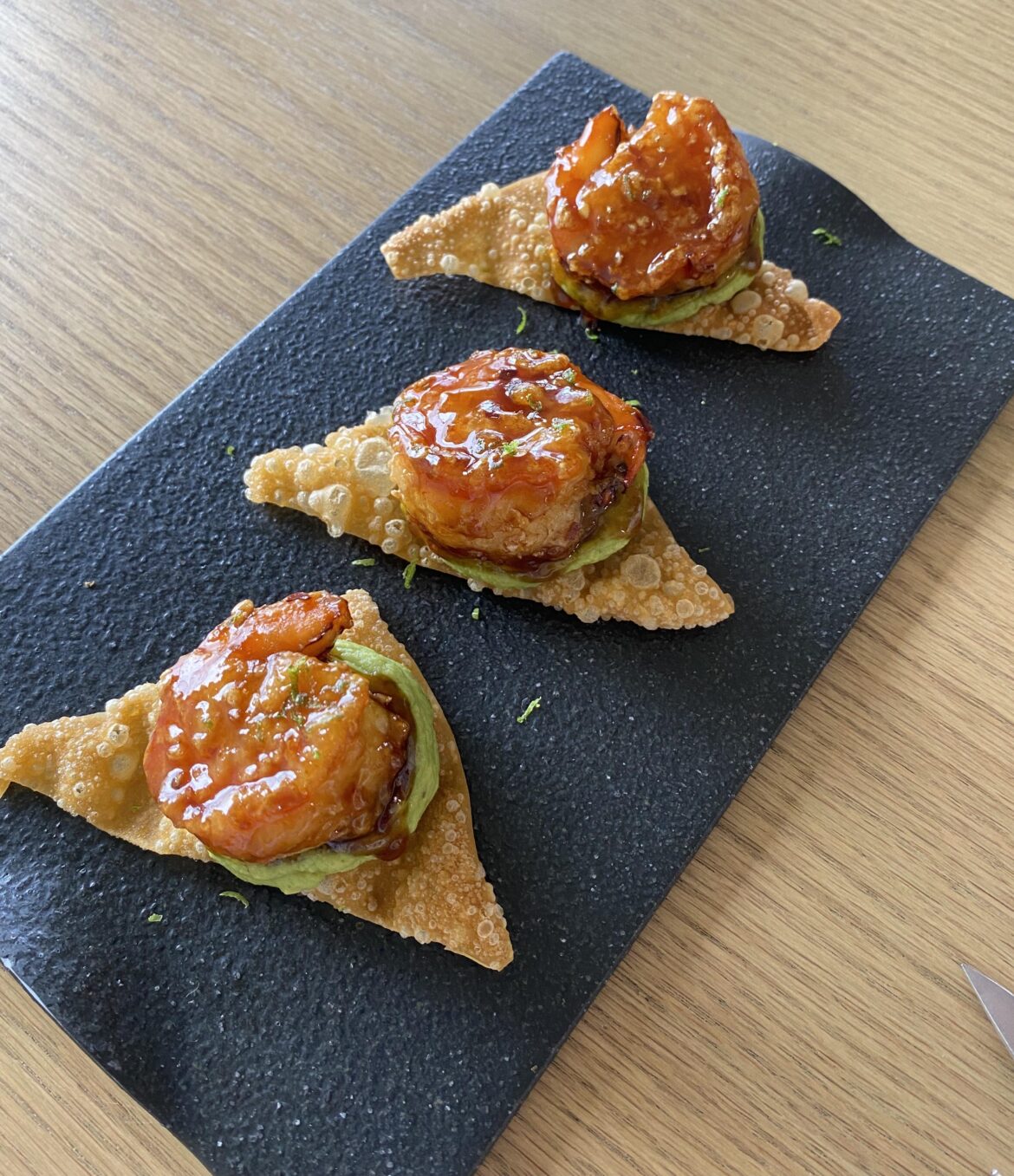 Honey soy glazed shrimp over avacado purée on a fried wonton, zested with lime