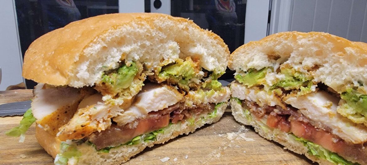 Sous vide Adobo chicken, fried avocado, bacon, tomato, lettuce, and cilantro lime aioli on torta bread