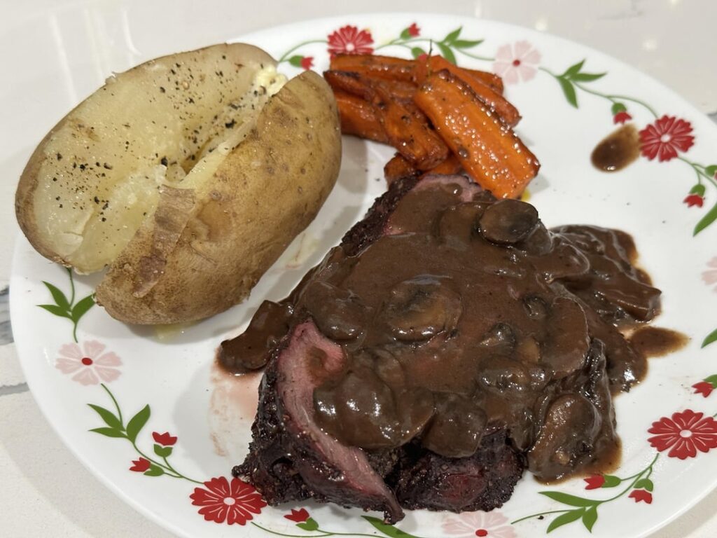 beef tenderloin w/mushroom gravy. baked potato and honey glazed carrots on the side.