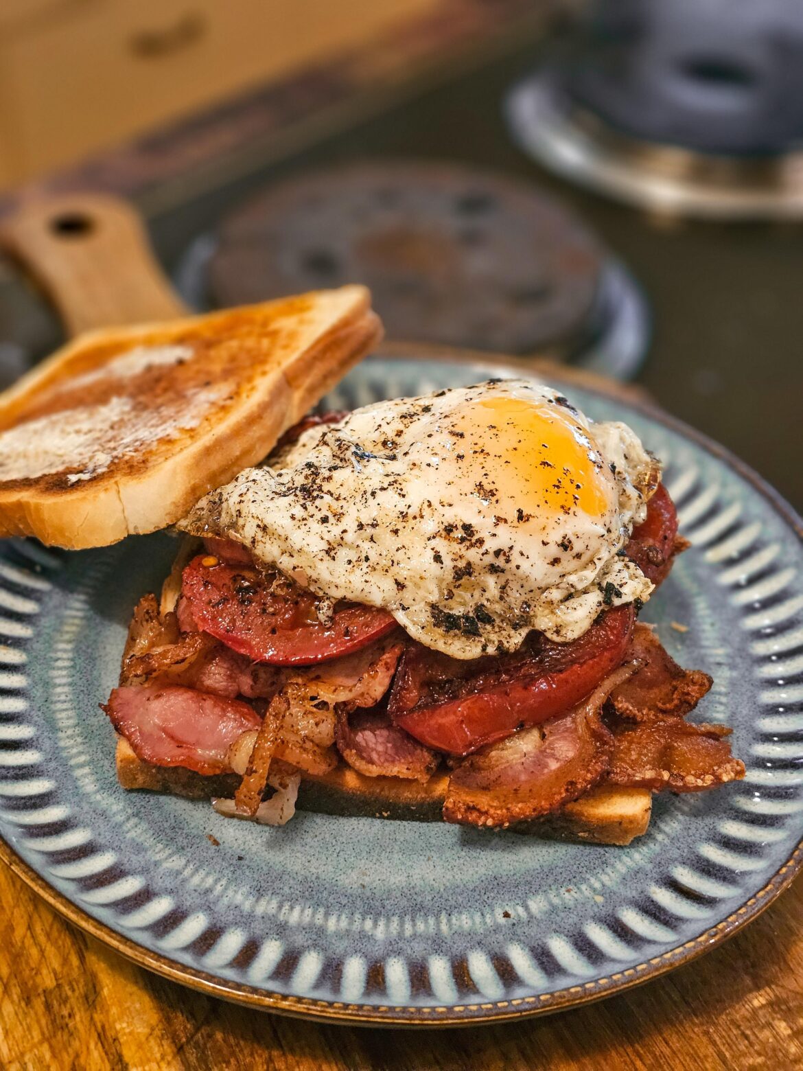Simple comfort breakfast food; Bacon, grilled tomatoes, and egg on toast.