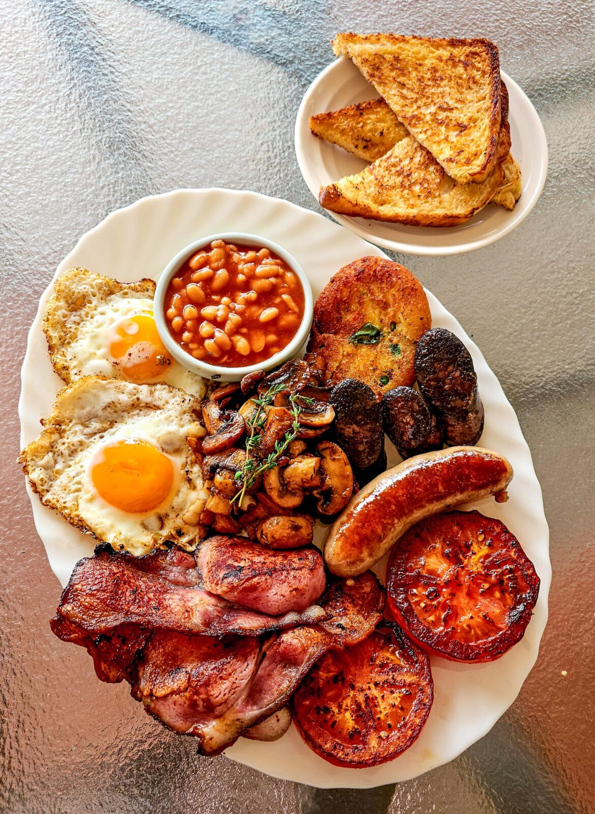 [Homemade] Full English Breakfast with pork sausage, smoked bacon, fried eggs, grilled tomatoes, thyme and sage mushrooms, fried bread, bubble and squeak, black pudding, and baked beans.