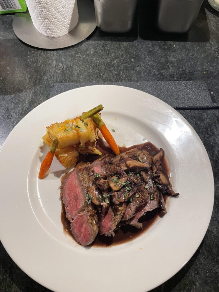 Pan-Seared NY Strip with shiitake mushroom pan sauce. Pomme pave potato, and sous-vide carrots with maple caramel glaze