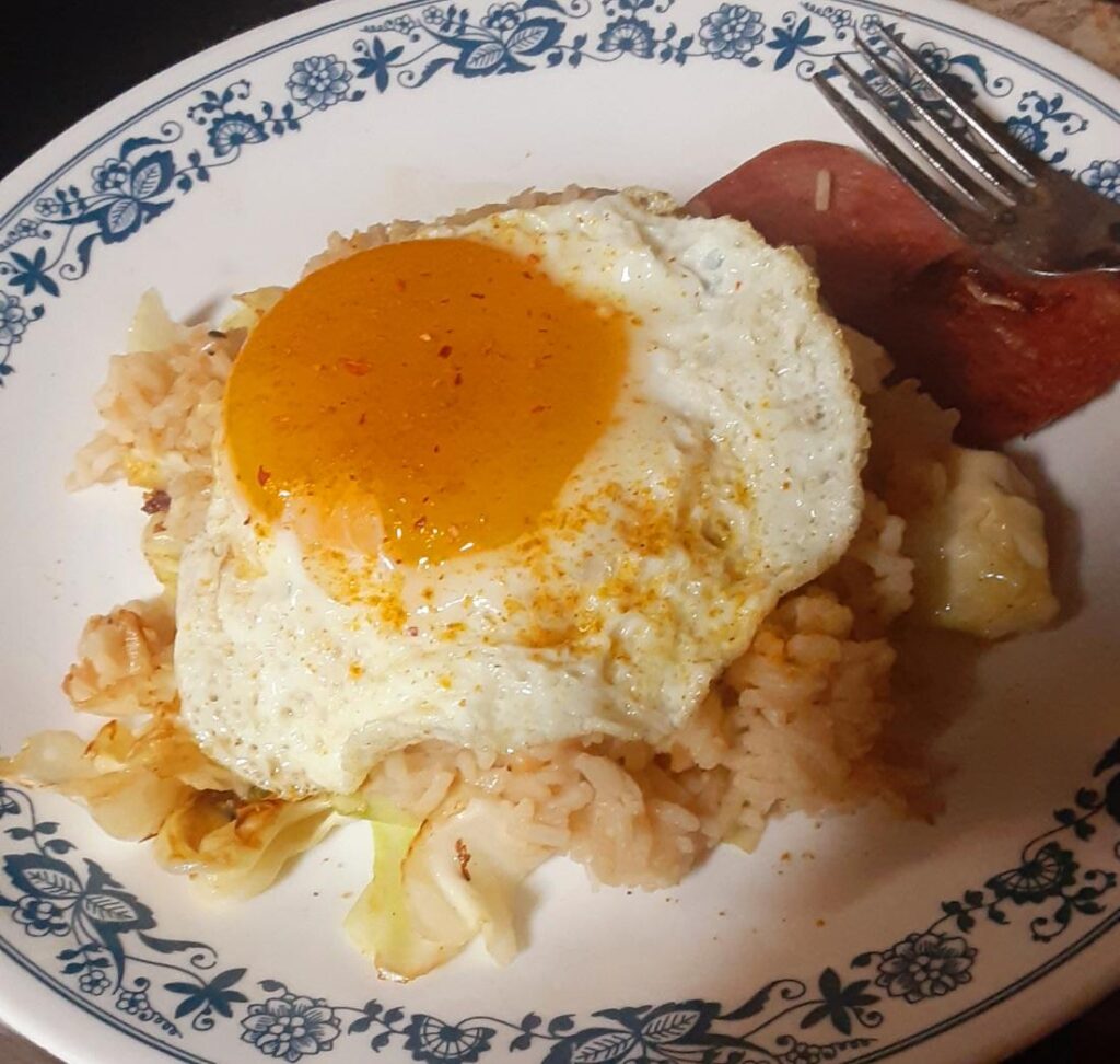 Duck egg on rice over fried cabbage with a dusting of red pepper and curry powder.