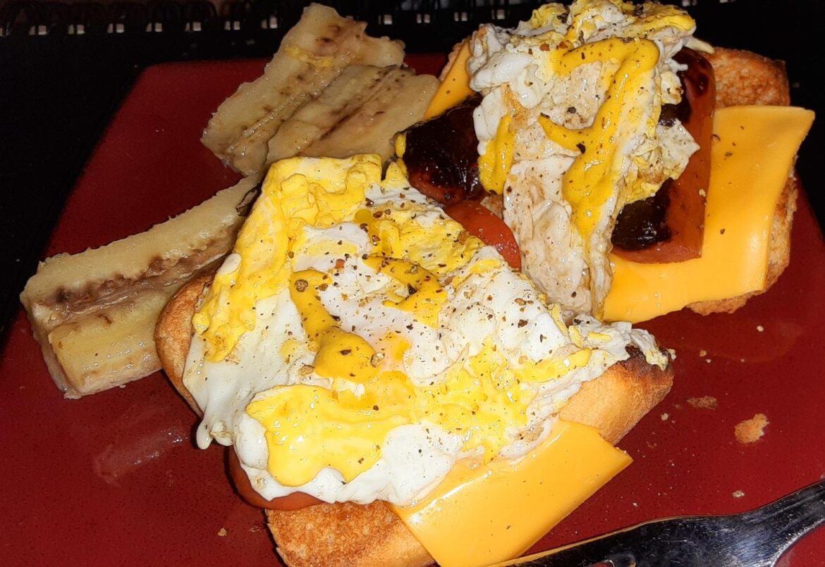 Breakfast Hot Dogs: Scrambled egg on top of split fried weenies and toasted buns with cheese. Also a side of fried banana.