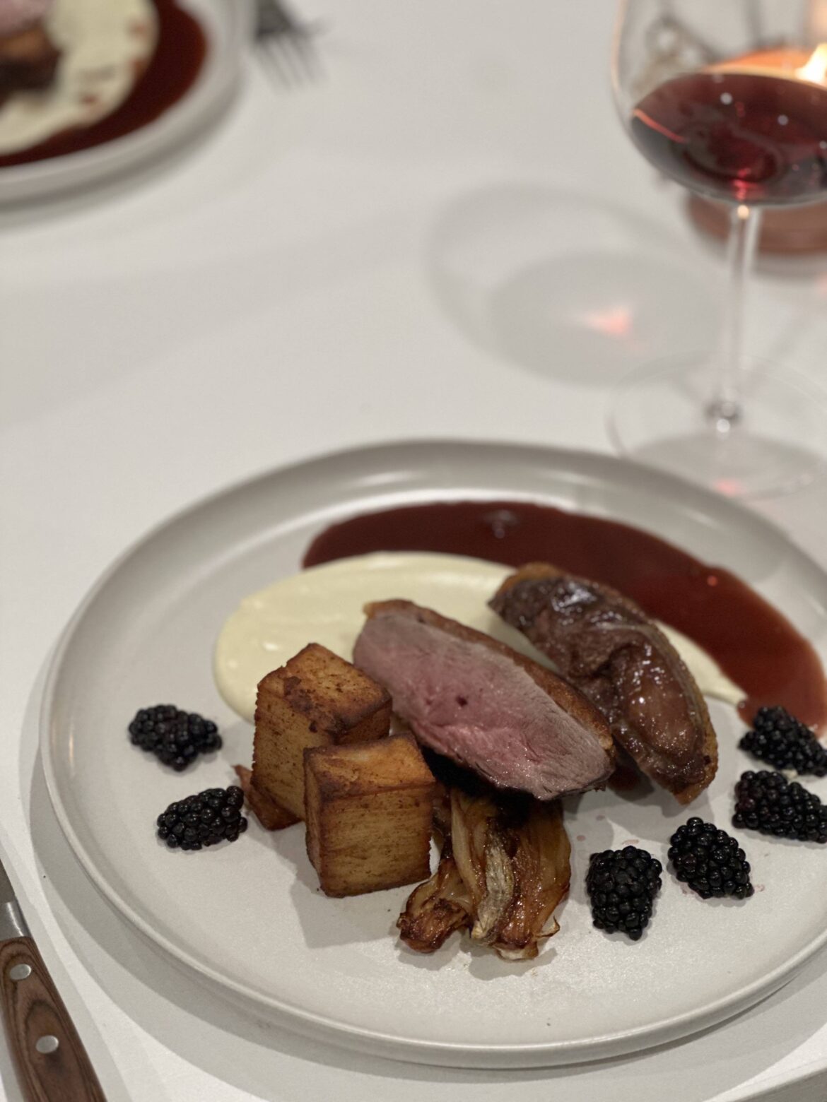 Duck with blackberry red wine Demi + orange braised endives, duck fat potato pave and cauliflower purée