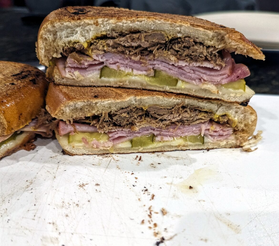 Cuban sandwich with pulled pork, pressed between 2 cast iron pans