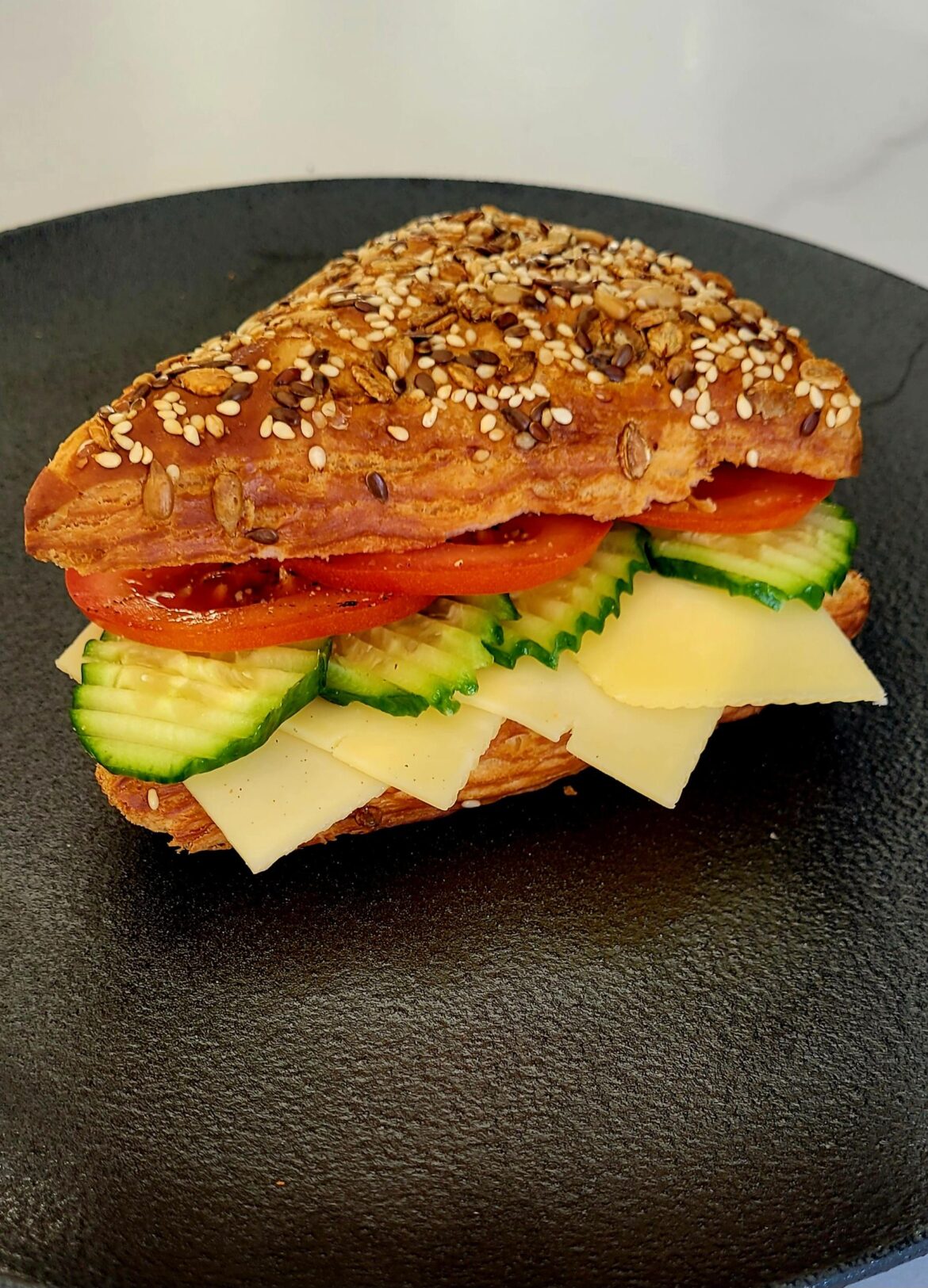 Cheese, cucumber and tomato on a lye croissant roll