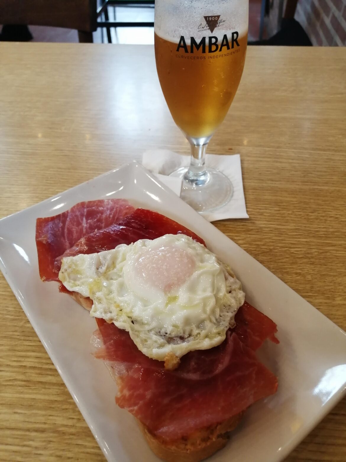 Toasted bread with tomatoe, spanish serrano ham and fried egg in olive oil.