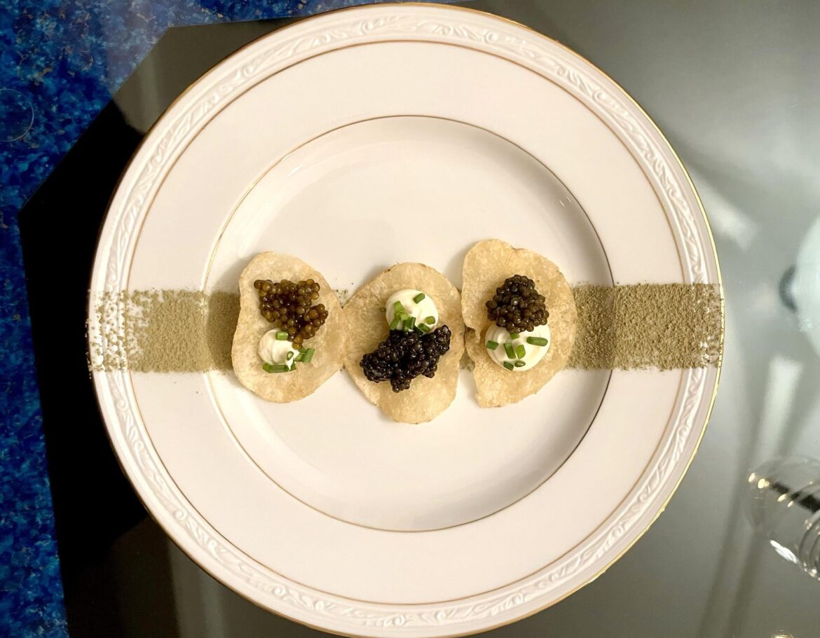 Caviar, chives, and creme fraiche on a potato chip over matcha dusting.