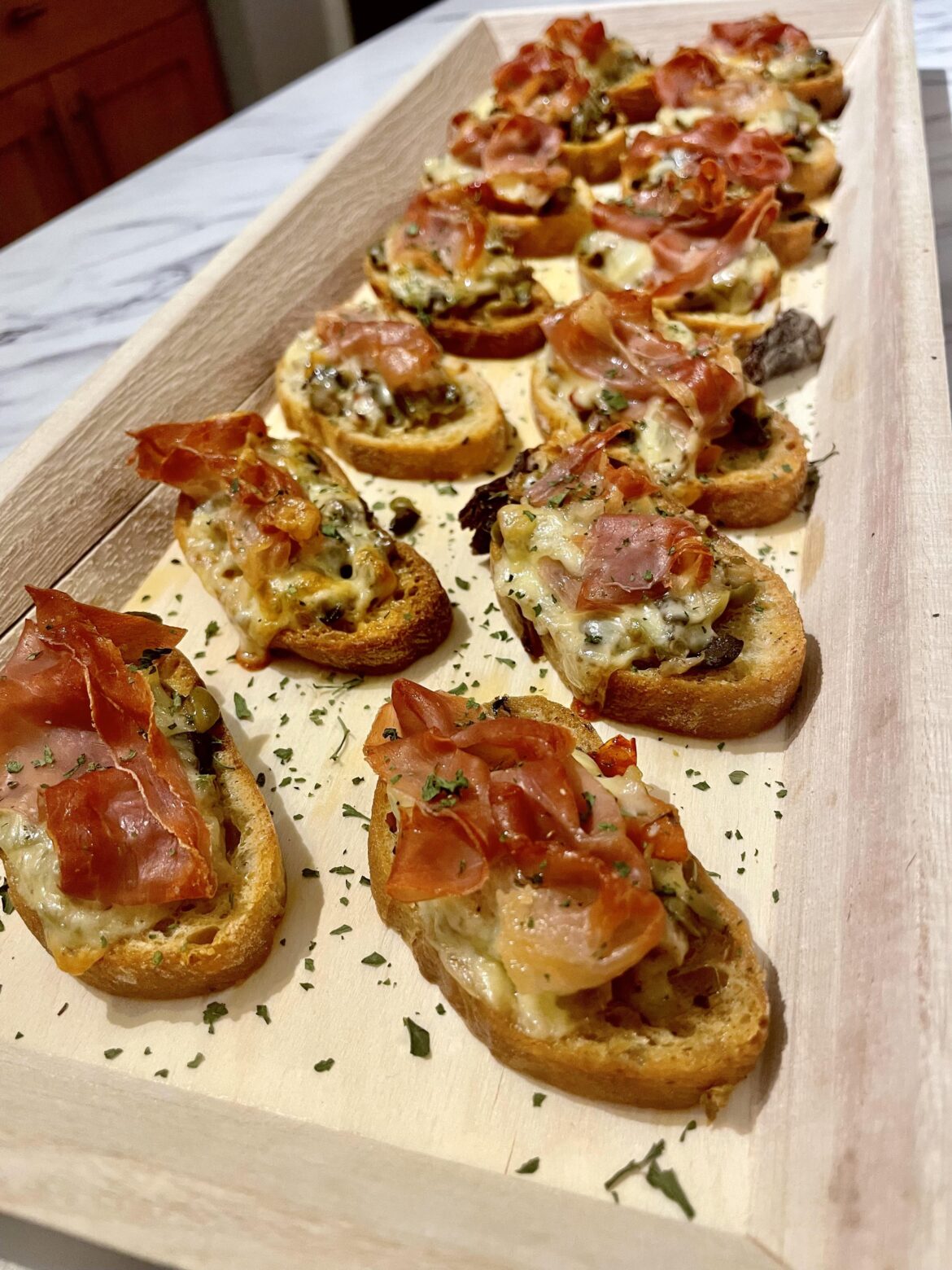 Crostini with olive tapenade, smoked gouda and prosciutto