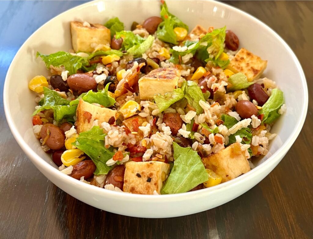 Brown rice with crispy tofu, roasted corn, pinto beans, green lettuce, and spicy salsa.