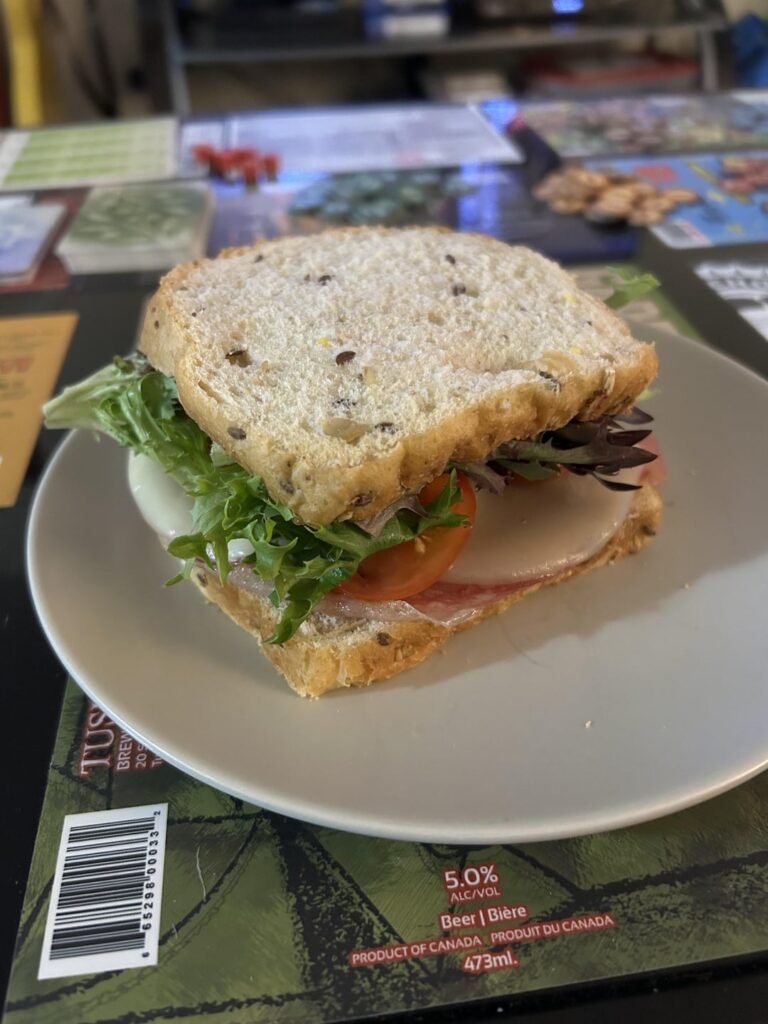 Simple deli meat sandwich with tomato, baby lettuce, banana peppers, and Dijon