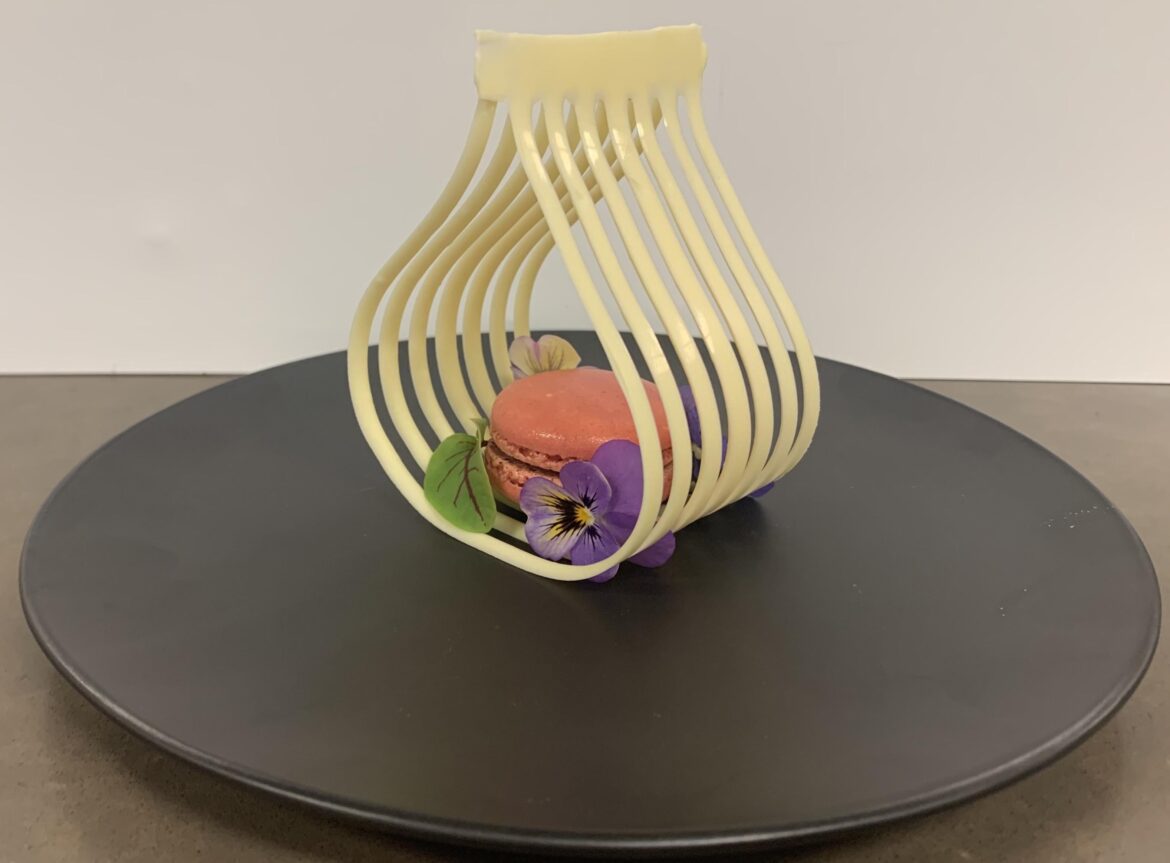 White chocolate and raspberry macaron, white chocolate decoration, sorrel and edible flowers.