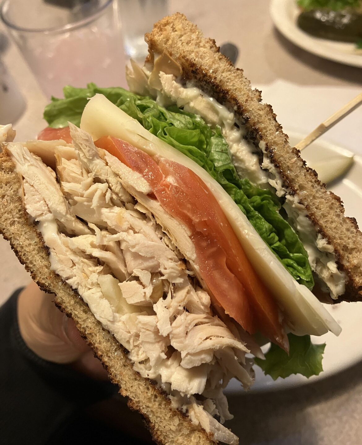 Roast turkey sandwich with lettuce, tomato, Swiss cheese, and mayonnaise on a toasted whole wheat bread.