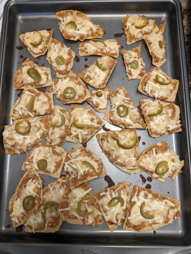 Nachos with refried beans mixed with ghost pepper salsa. Topped with Carolina reaper cheese and jalapeños