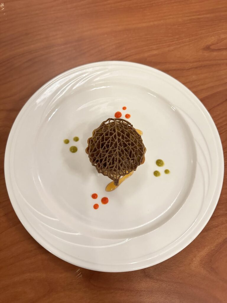 Black Apple Honey Amuse with a Coffee Shoyu Tuille, Served With Fresno & Serrano Hot Sauce