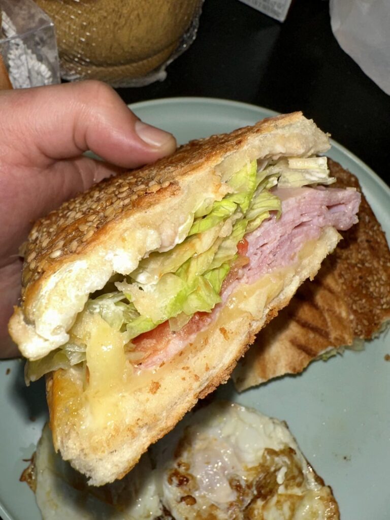 Ham and Swiss with, mayo, ketchup, lettuce, tomatoes, salt, pepper, oil and vinegar on a sesame club roll.