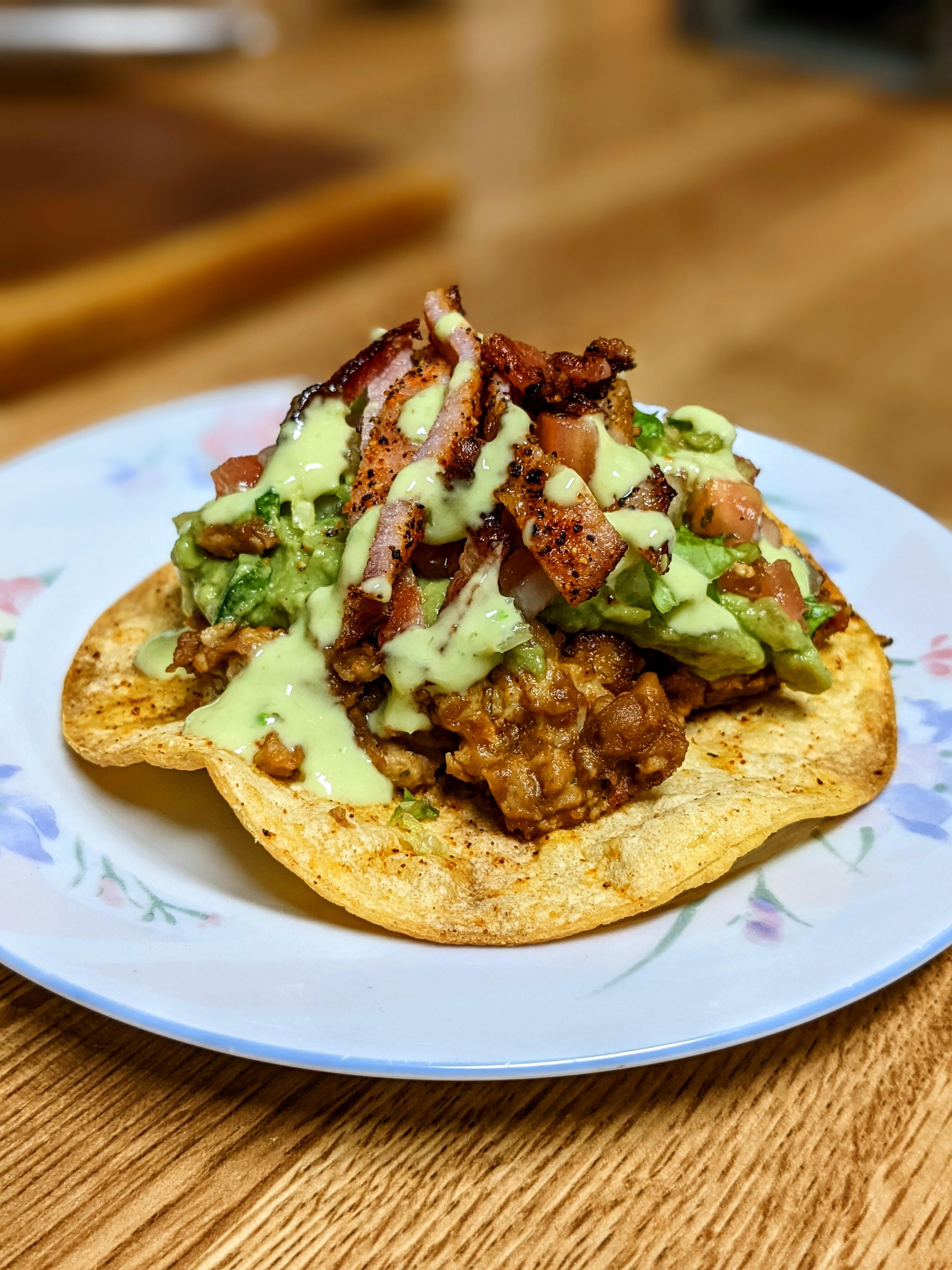 Tostada with pinto beans, chicken, guacamole, pico, lettuce, avocado