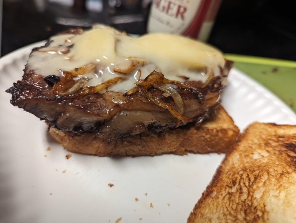 Prime rib sandwich with sauteed onions and garlic with white cheddar on sourdough