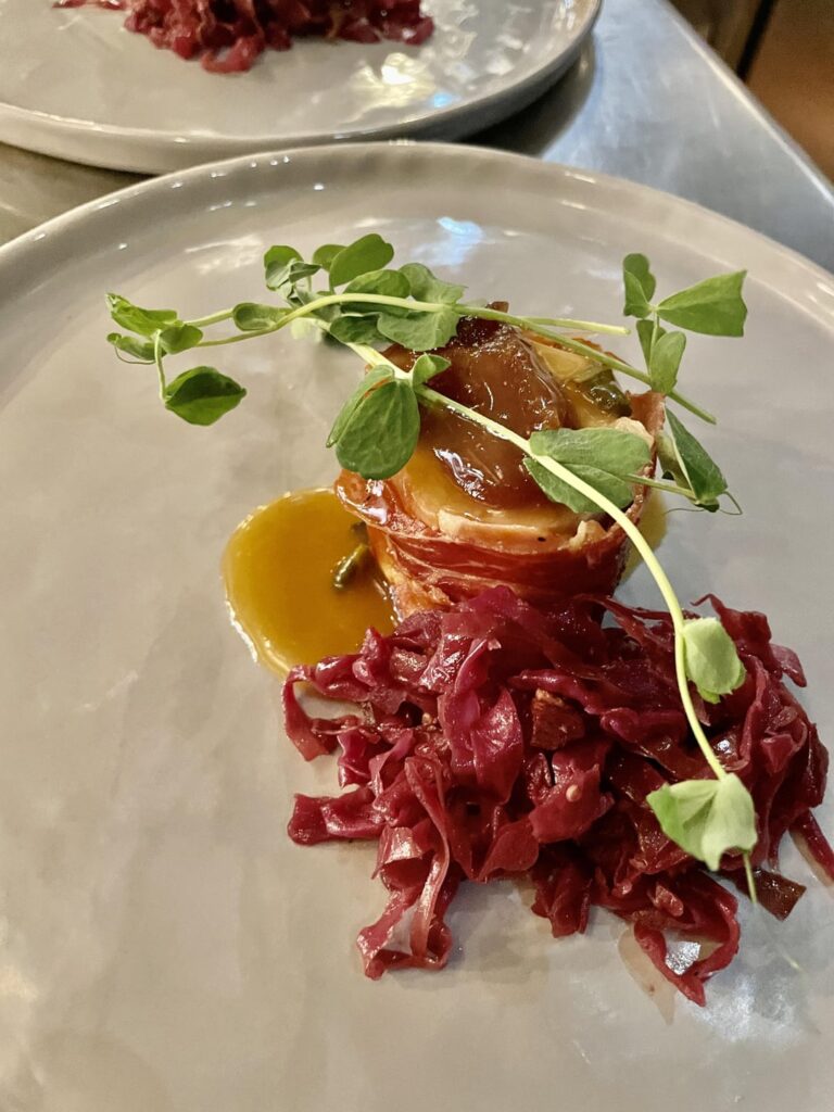 Prosciutto wrapped pork tenderloin with apple butter, sage sauce, & braised red cabbage