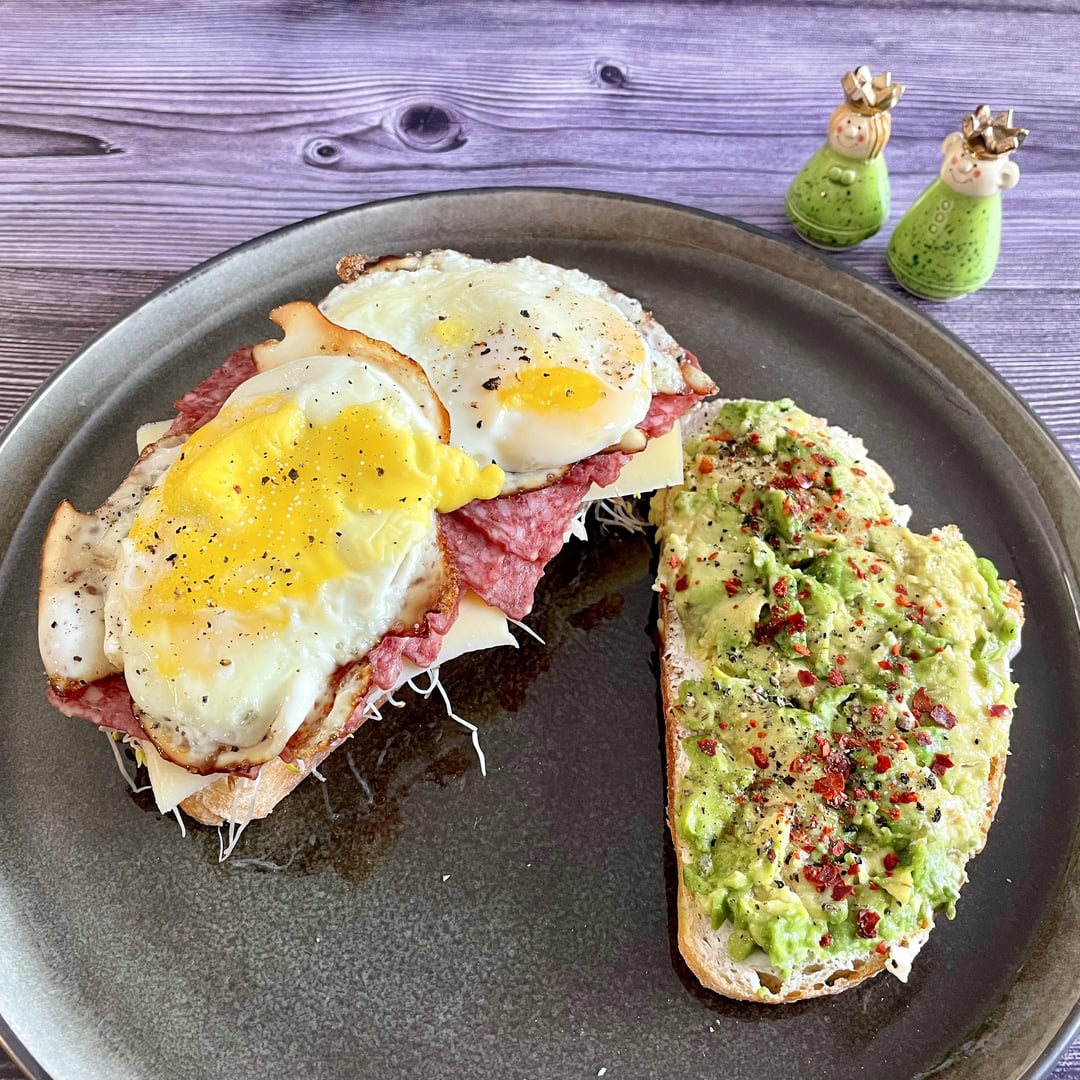 Breakfast sandwich with fried eggs, salami, gouda cheese, alfalfa