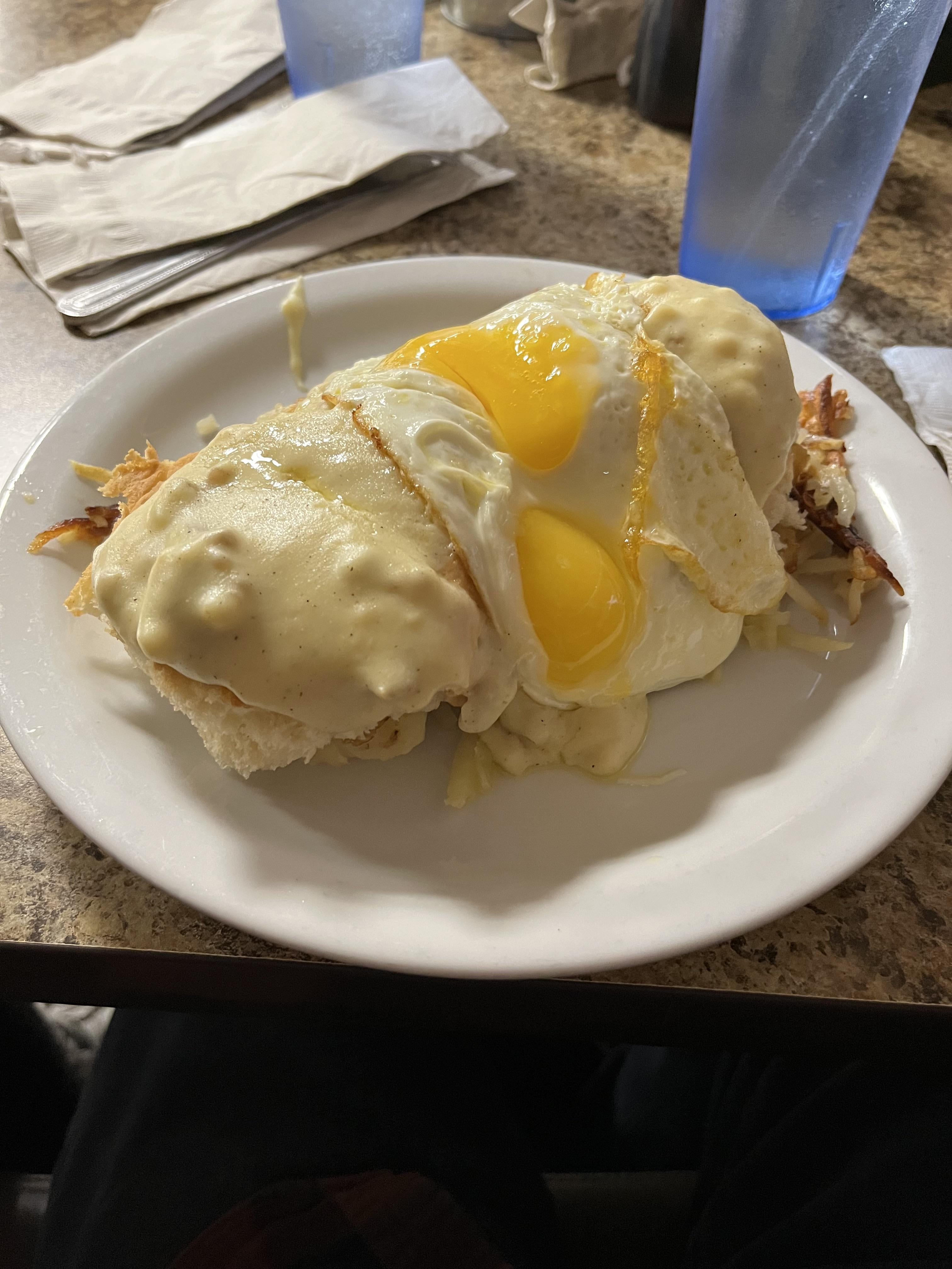 Biscuits and gravy on hash browns with fried eggs on top Dining and