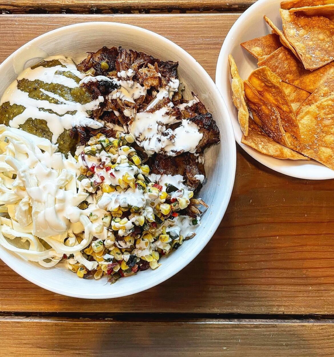 Kenji’s carnitas, in burrito bowl form, along with his charred salsa verde, some corn salsa, cheese, crema, some buried cilantro like rice, and home fried tortilla chips.