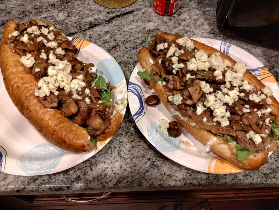 Prime rib sandwiches with arugula, sautéed onions and mushrooms, creamy horseradish sauce, and topped with bleu cheese crumbles
