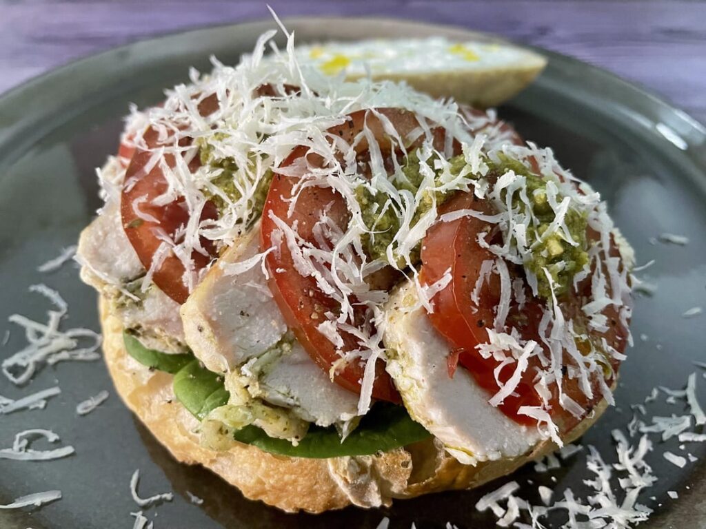 Italian-Portuguese sandwich: mozzarella and pesto filled chicken from yesterdays dinner, spinach leaves, tomatoes, more pesto and parmesan. All on a Portuguese bun, spiced up with piri piri oil
