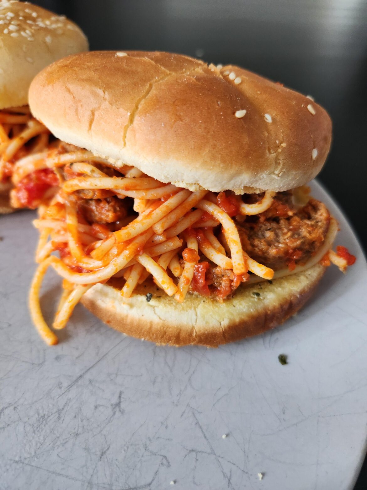 Spaghetti and meatball sandwich on garlic toast bun.