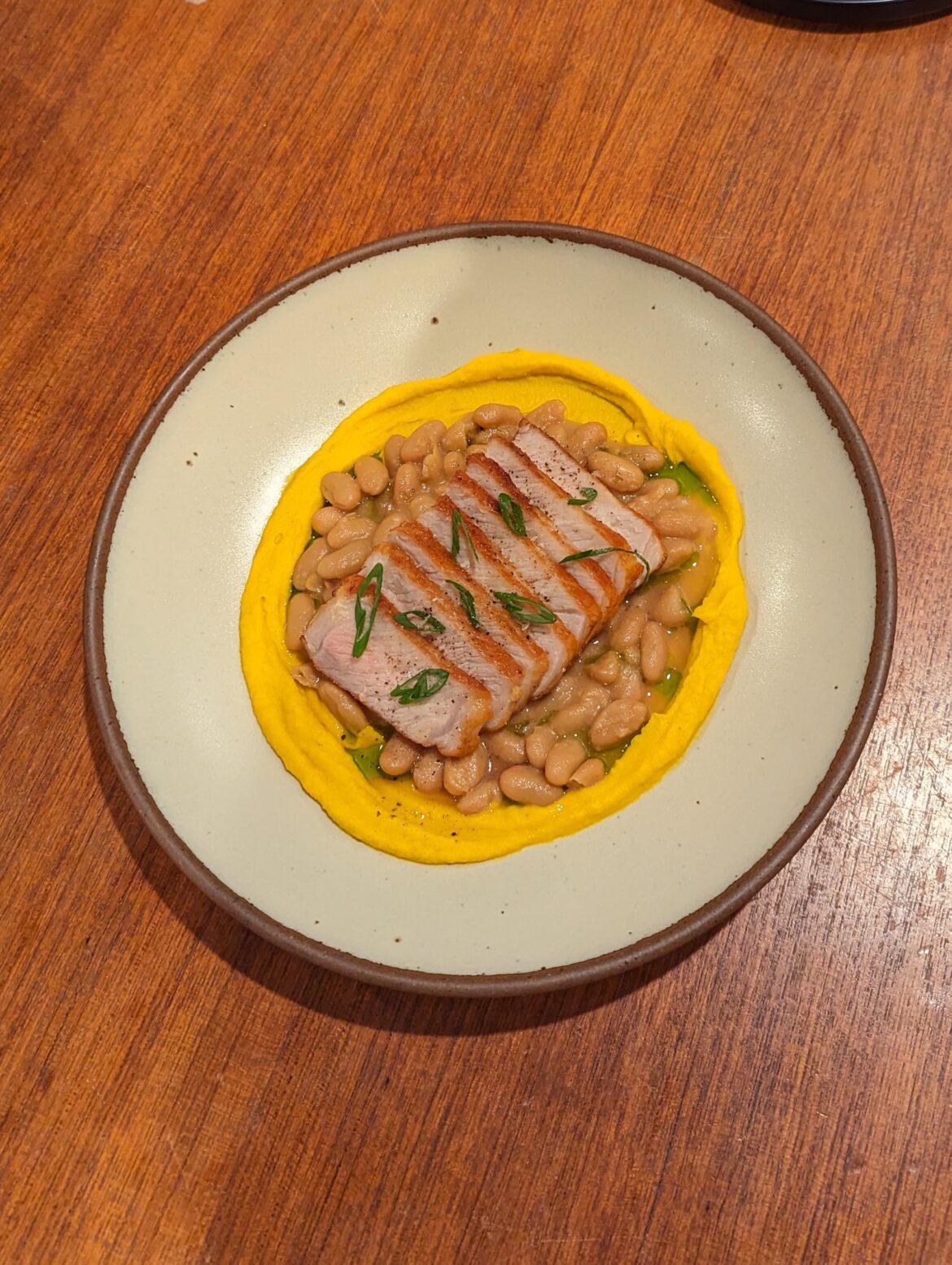 Pan seared pork chop over miso, soy, and mirin glazed cannellini beans with a kabocha squash puree