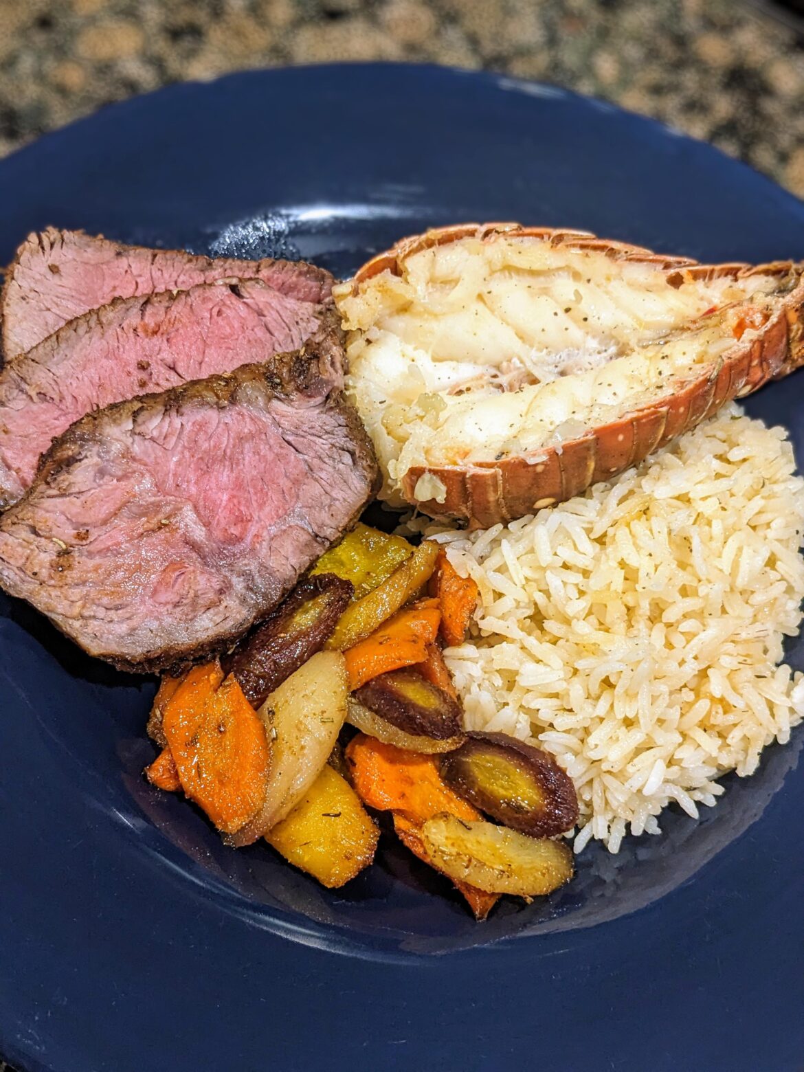 Garlic butter poached lobster, sirloin steak, roasted rainbow carrots & rice