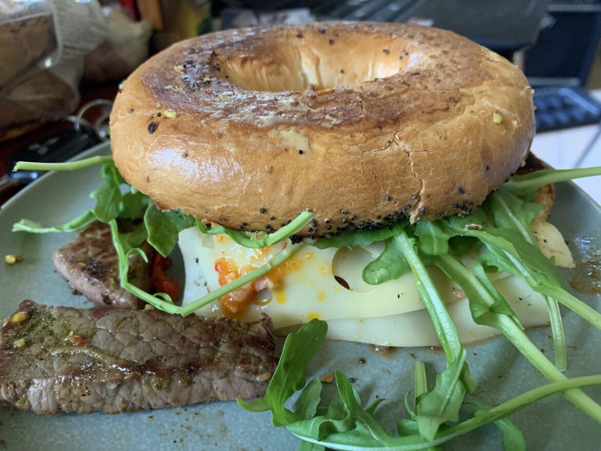 This is a steak&swiss&chilli jam bagel with arugula and horseradish.