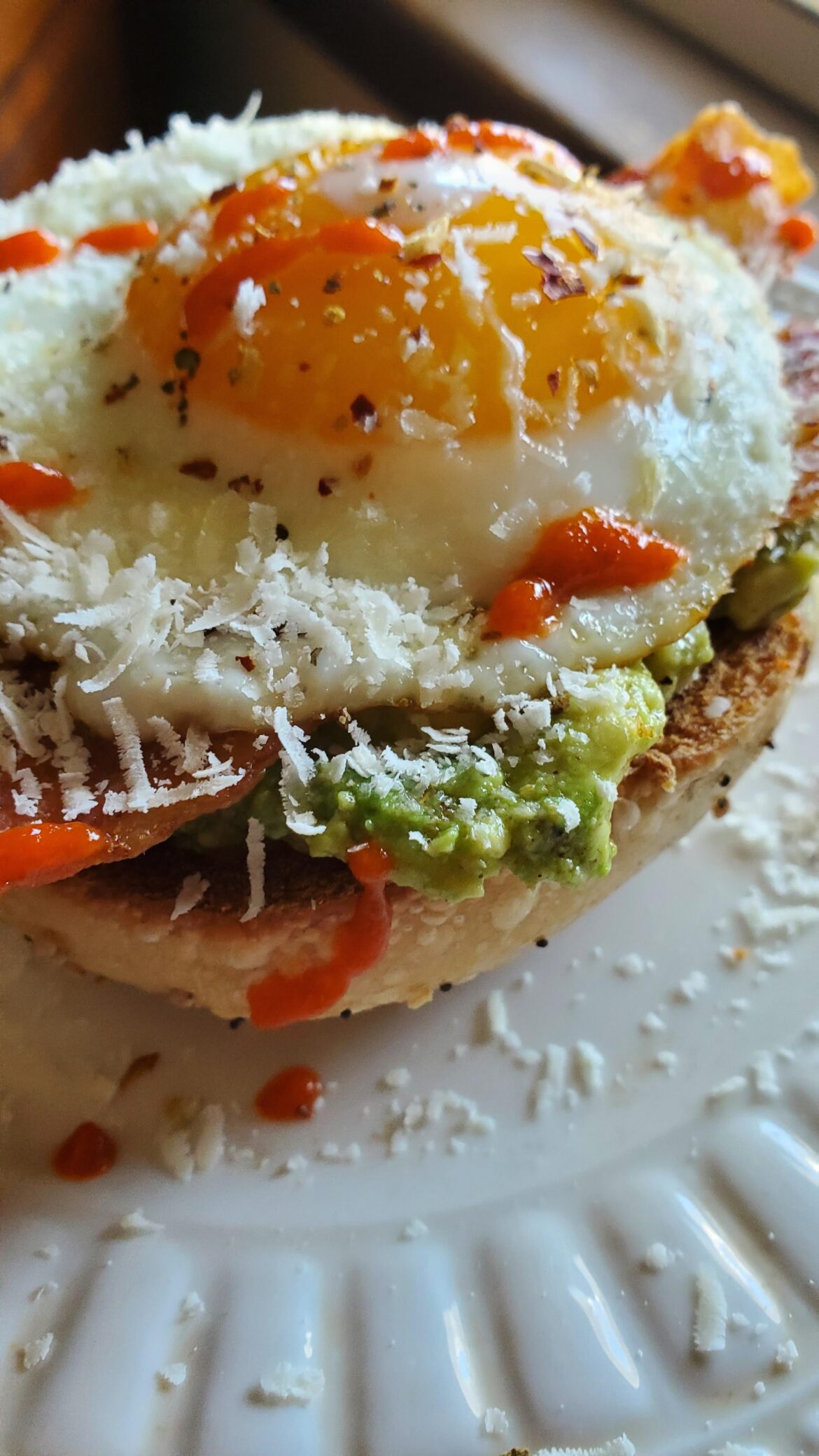 Sunny side up egg, bacon, guacamole on toasted bagel.