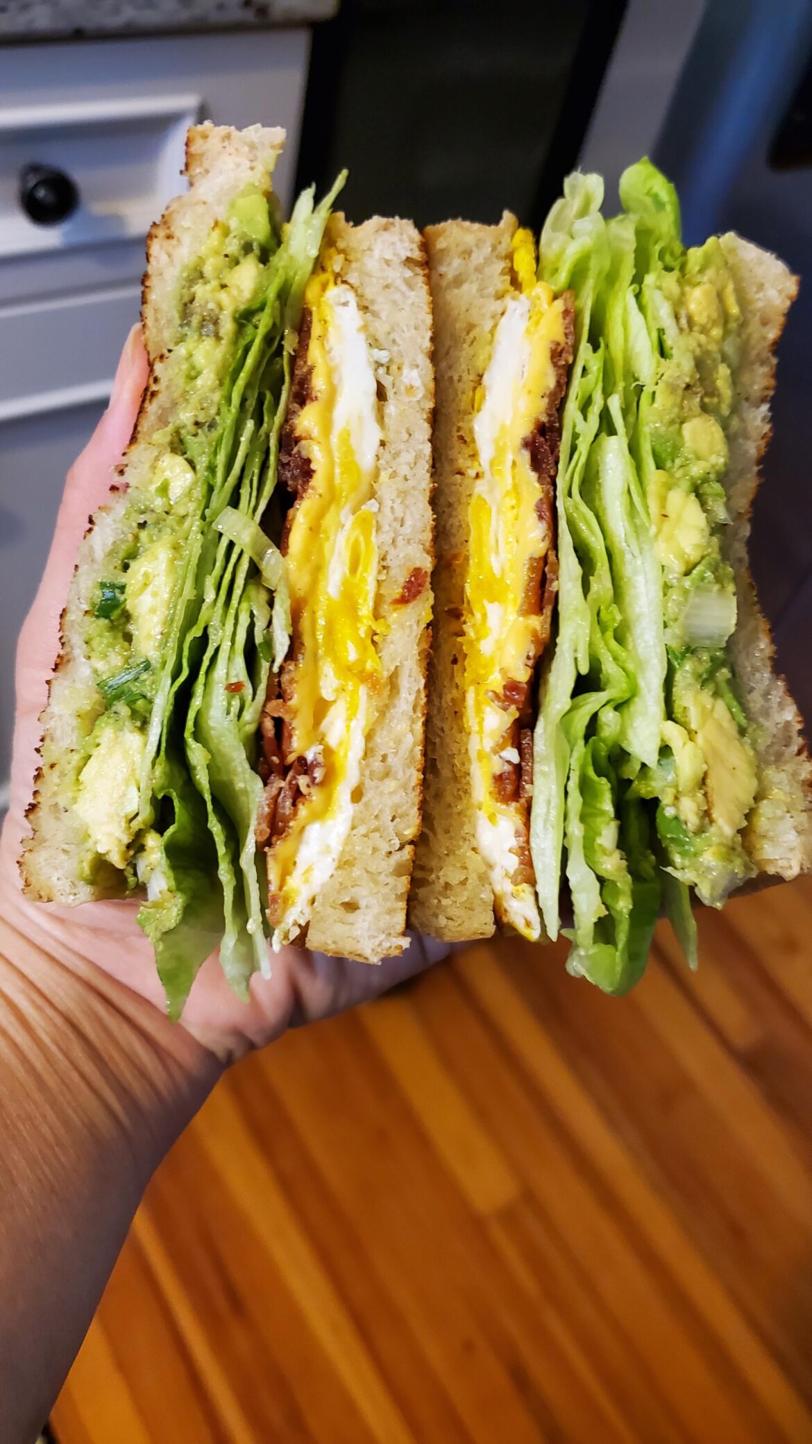 Made a breakfast sandwich. Bacon egg cheese sandwich with guacamole and crispy lettuce on toasted sourdough bread.