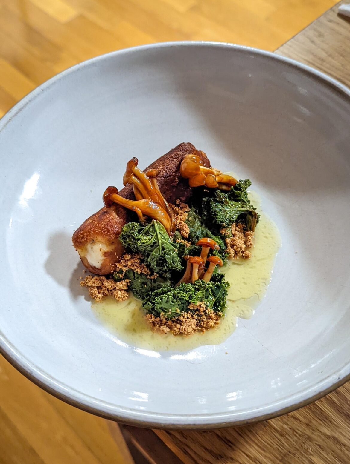 Brioche crusted fish with garlic kale bread pudding, braised mushroom, and a burnt kombu oil beurre blance