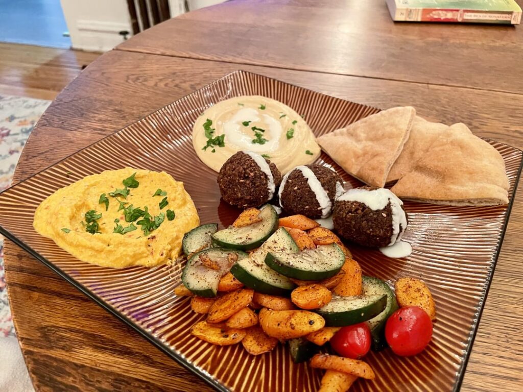 Mezze featuring hummus, tirokafteri, sumac roasted veg, falafel, and wholewheat pita