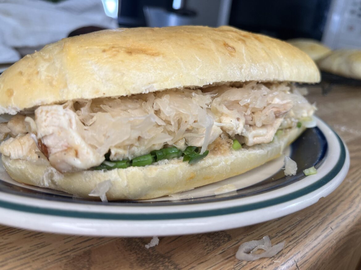 Homemade hoagie roll, rotisserie chicken mixed with mozzarella to melt, thousand island, green onion, sauerkraut
