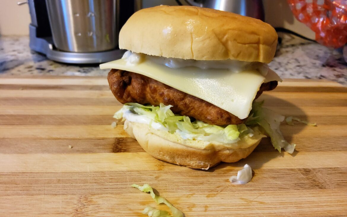 Battered fried cod sandwich with lettuce,  cheese,  and tartar sauce.