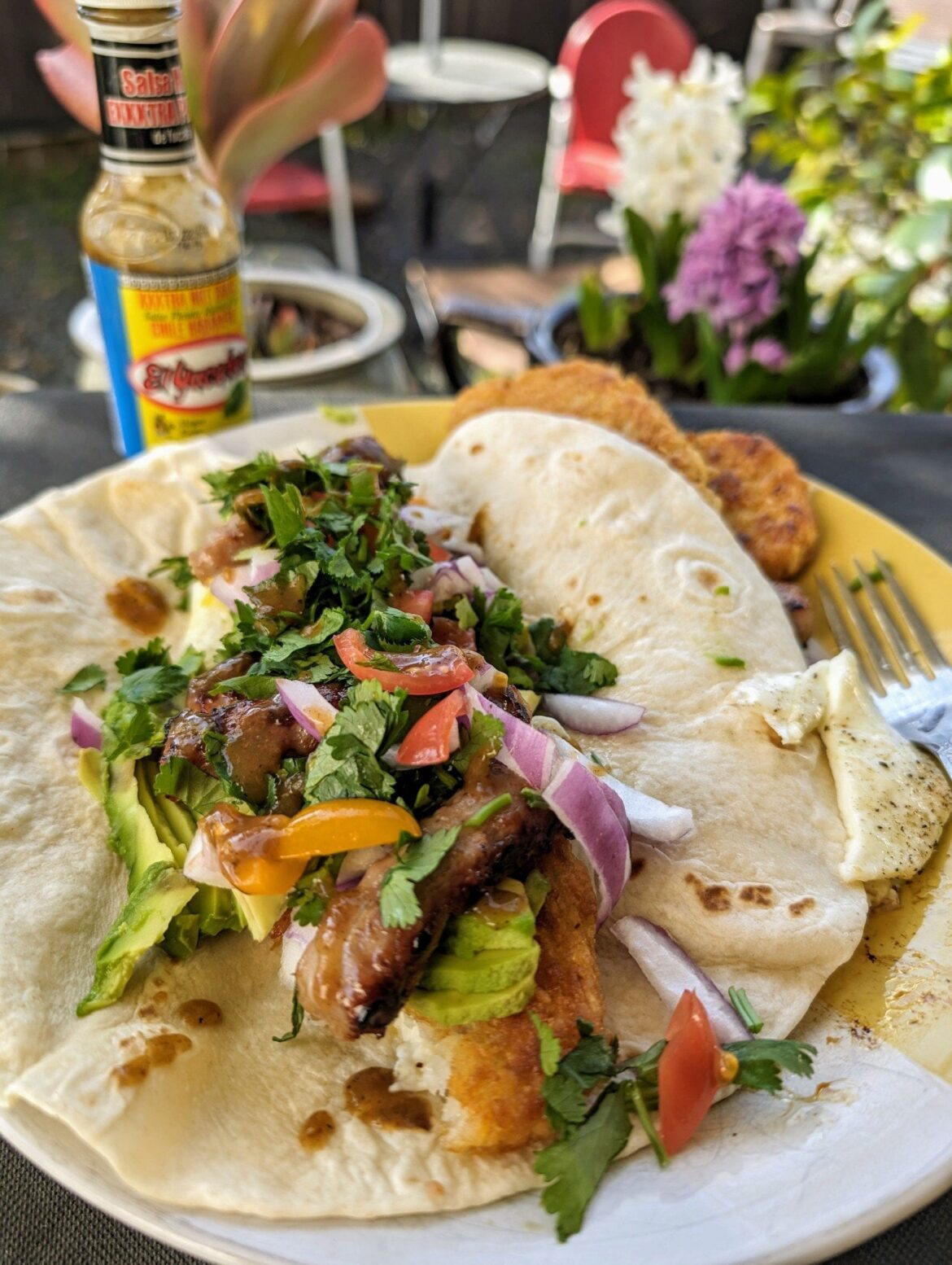 Breakfast burrito with an over easy egg, hash browns, avocado, cilantro, red onion, and El Yucateco XXXtra hot.