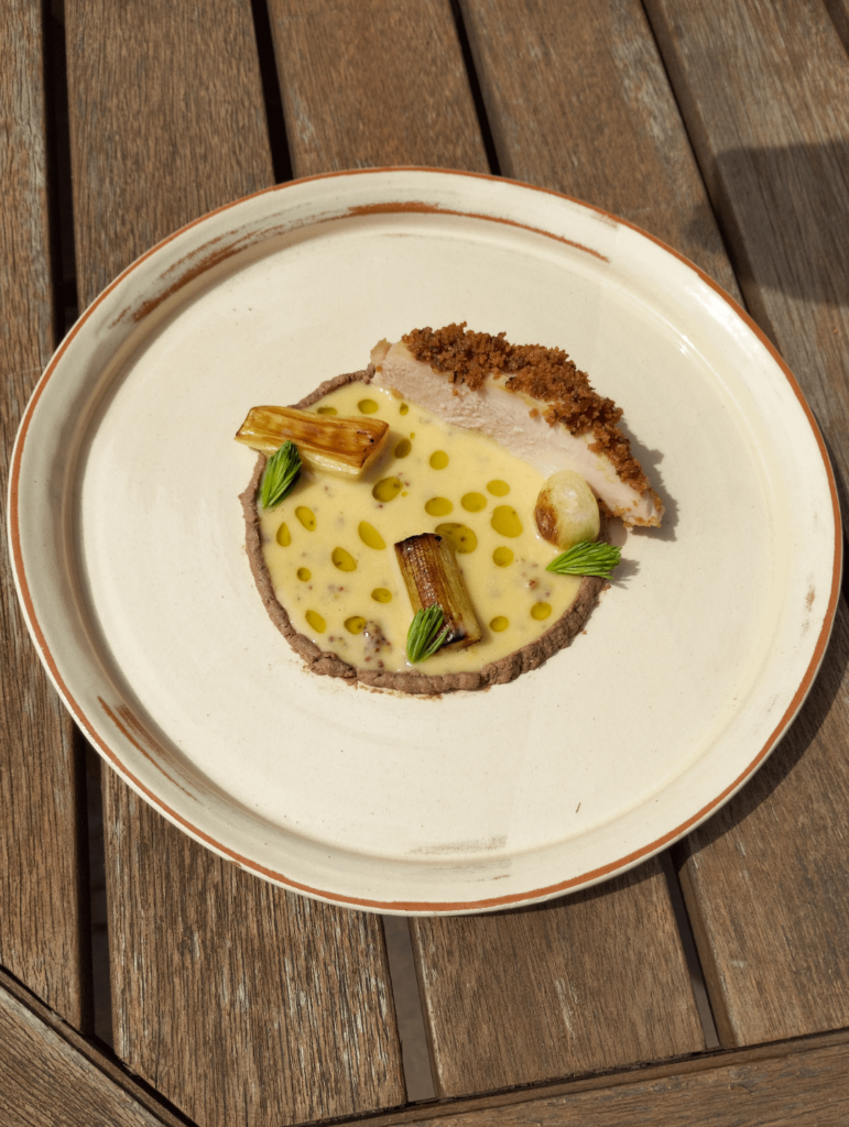 Chicken breast with sage-chicken skin crumble,  green onion segments, beurre blanc, chicken liver paté and pine sprouts.