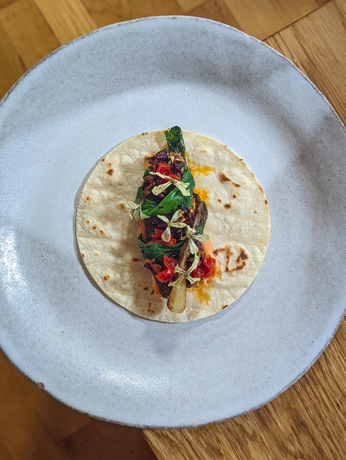 Seared trout with roasted ramp, arugula flowers, salsa macha, and fermented scotch bonnets