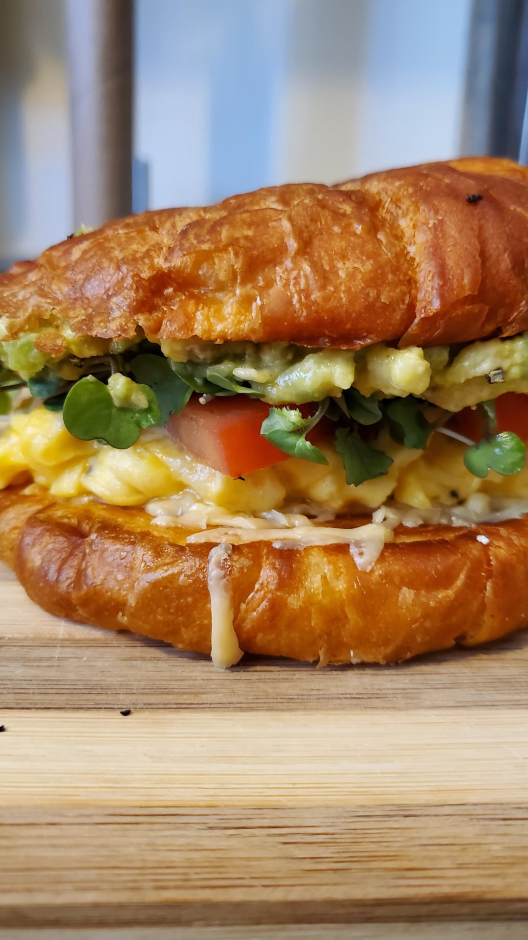 Scramble egg croissant breakfast sandwich with guacamole, gouda cheese