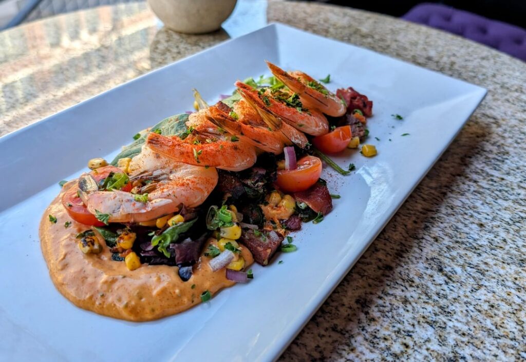 Poached Chilled shrimp, Remoulade, mixed greens, cherry tomatoes, Tasso, Crispy house made andouille, roasted corn and poblano, Citrus viniagrette, paprika