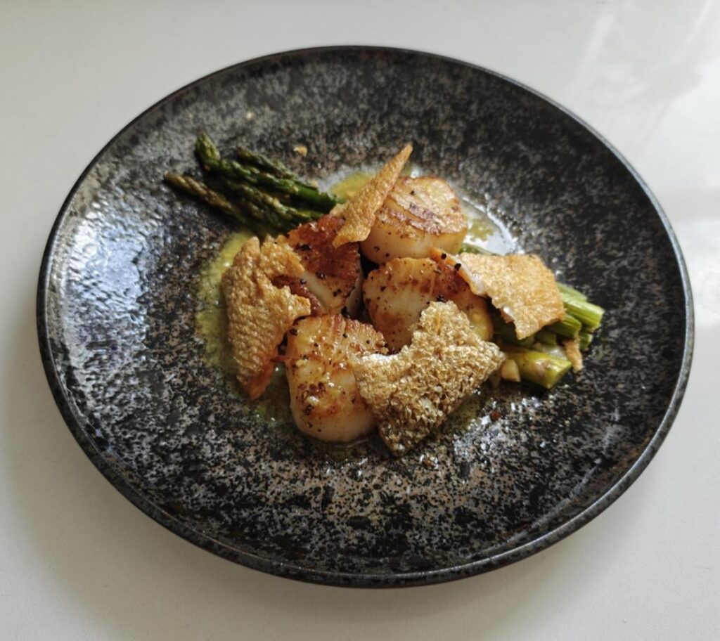 Seared scallop, sautéed asparagus, and honey miso sauce with salmon skin chips