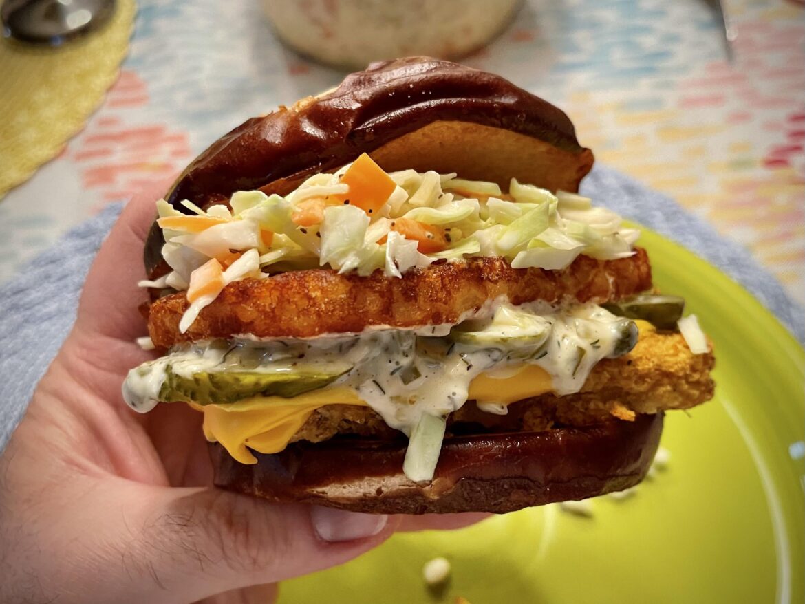 Wisconsin fish fry sandwich: fried fish, American cheese, homemade tartar, pickles, potato pancake, and cole slaw on a pretzel bun