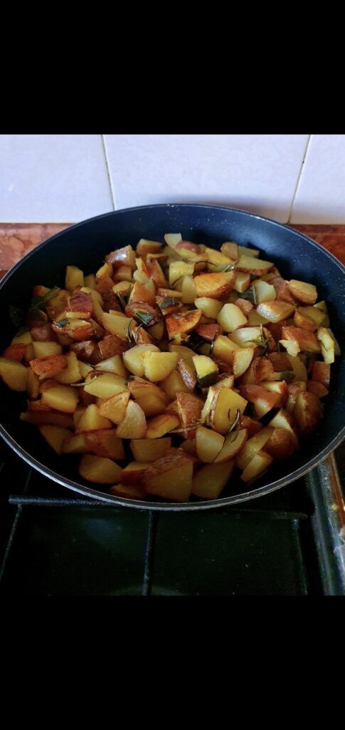 Potatoes with skin, red, yellow pasta in a pan with sage, rosemary