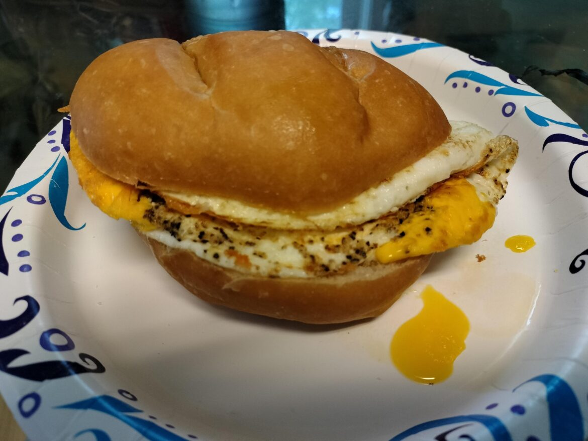 Simply a fried egg sandwich on buttered roll with cracked black pepper