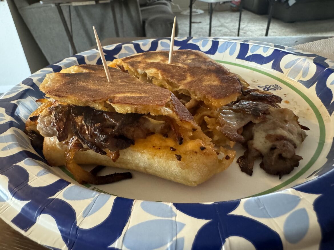 Tri-tip panini on ciabatta bread with sautéed onions, Swiss cheese and sriracha mayo