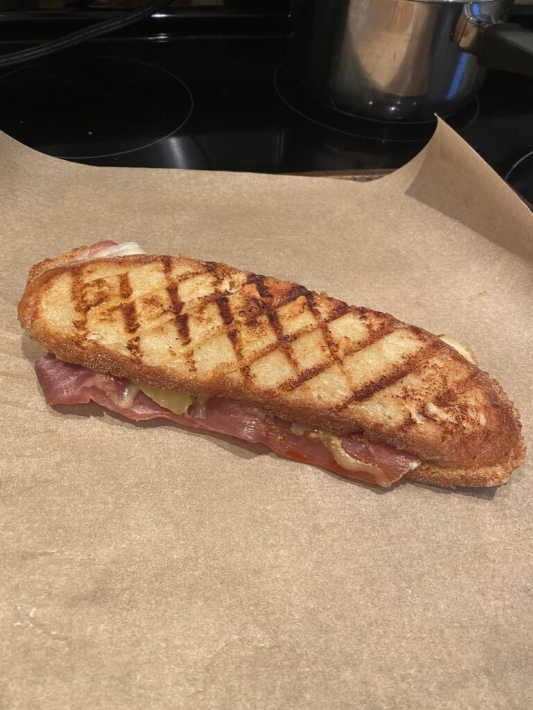 Prosciutto, onions, tomatoes, mozzarella, and hot Calabrian pepper paste on Calabrian bread; garlic paste spread on top and grilled